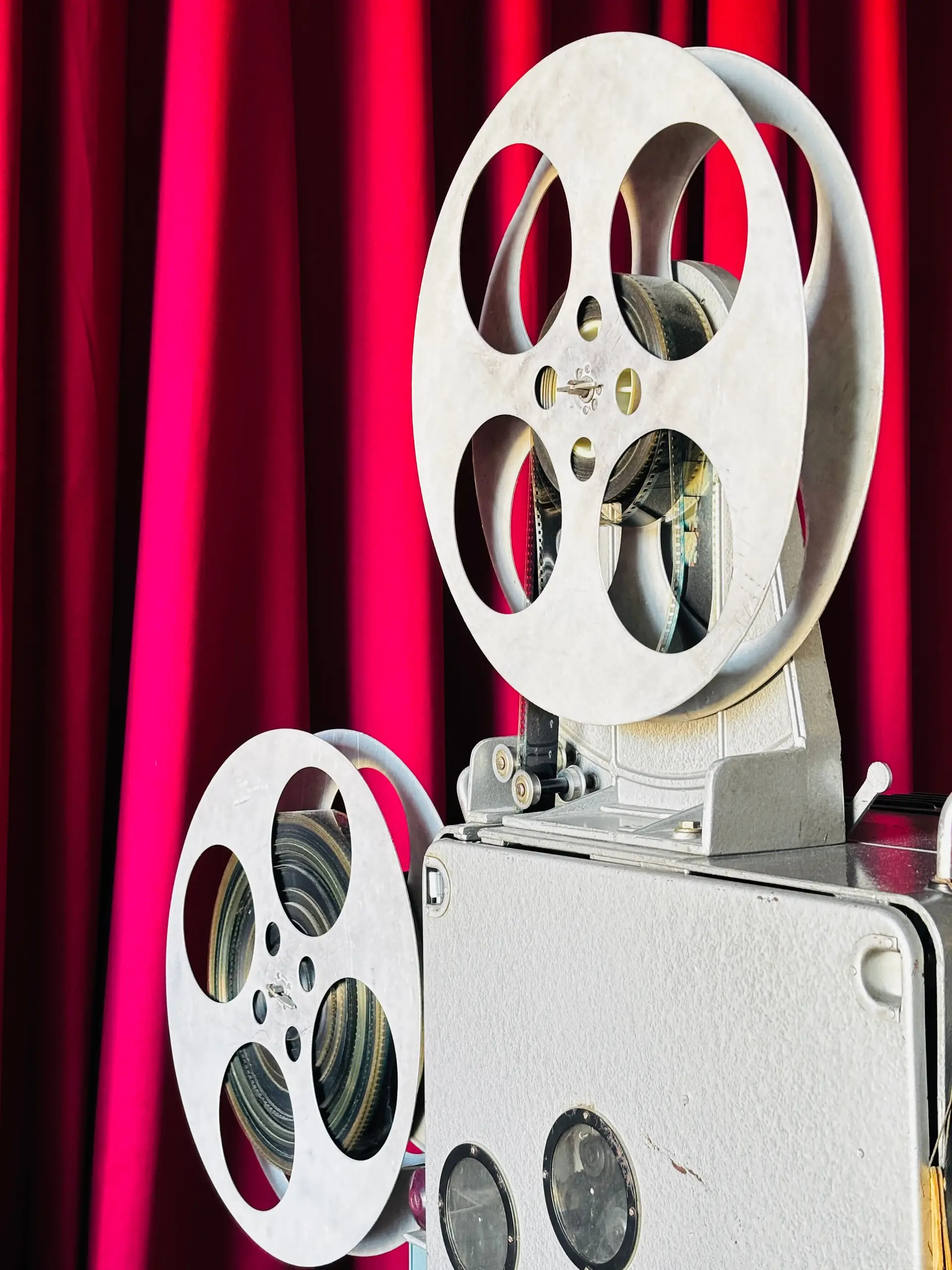 Klassischer Filmprojektor vor dunkelrotem Samtvorhang