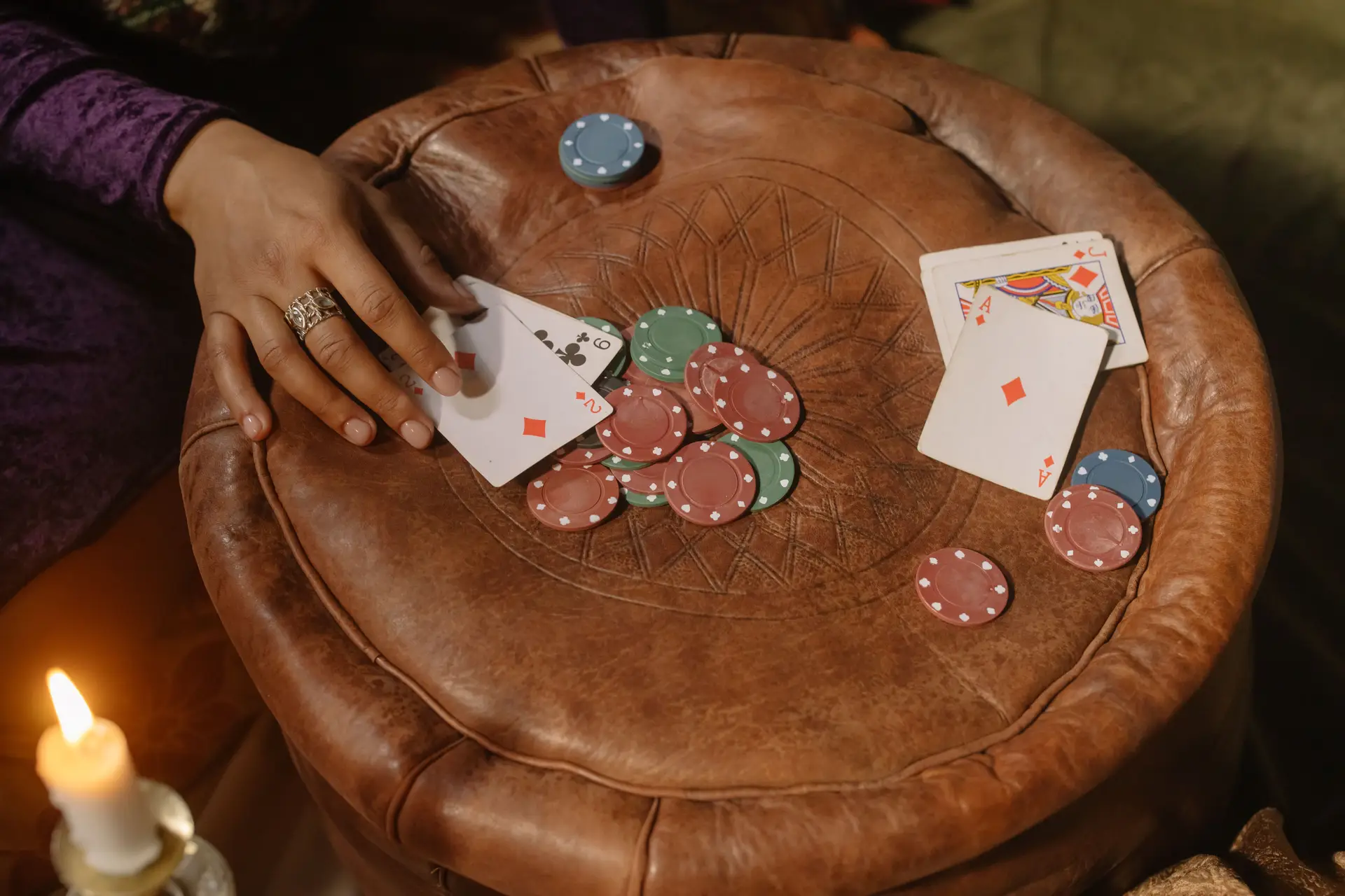 Hand mit Pokerchips und Karten in einer schummrigen Runde